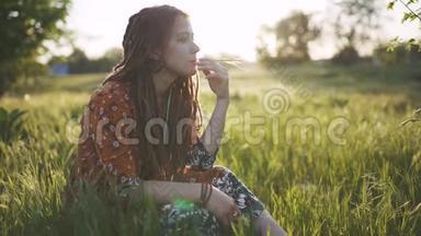 美丽的嬉皮士女人，在日落时带着绿草中的可怕的怪物，在户外玩得很开心